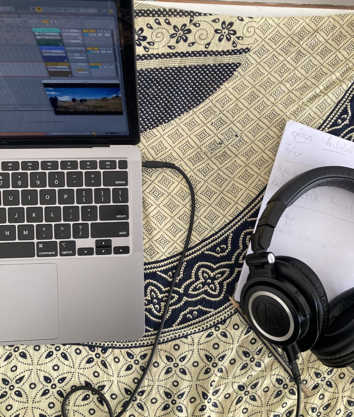 Escritorio de trabajo visto desde arriba, con laptop, auriculares y notas a mano
